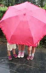 Kids hiding under an umbrella.