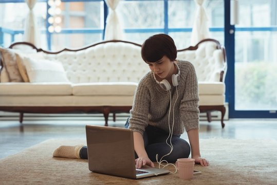 Woman with headphones using laptop in the living room