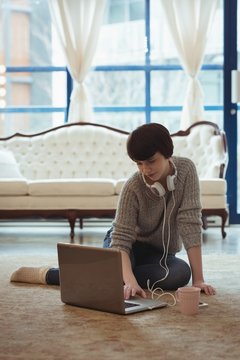 Woman with headphones using laptop at home