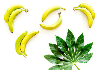 Tropical pattern with big leaf and bananas on white background top view