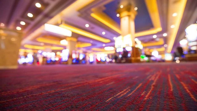 Low Angle Casino Floor Carpet No People Walking. low angle floor shot of a carpet in a casino with games and slot machines blurred in the background. Very little activity
