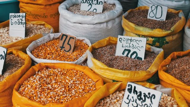 Many bags with different cereals on which hang the price tags stand on the market
