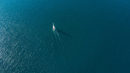 Aerial view on a yacht racing on quiet ocean on sunny day. Coromandel Peninsula, New Zealand
