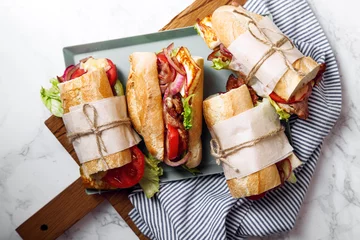 Papier peint photo Snack-bar Sandwich à la baguette fraîche de style bahn-mi. Bacon, fromage rôti, tomates et laitue sur plateau métallique sur fond de marbre blanc.  © Anastasiia Nurullina