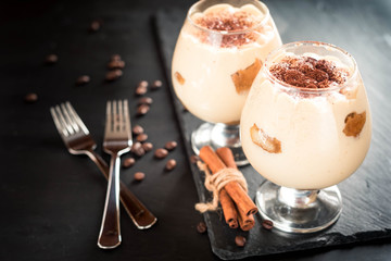 tiramisu in a glass decorated with coffee beans on a dark background