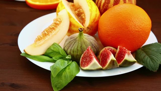 On the table lie fruit: Vietnamese melon, figs, kiwi, oranges, juice. Close-up. Hd shot with dolly from right to left.