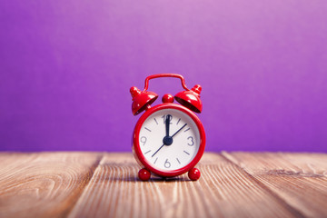 Red alarm clock on purple background
