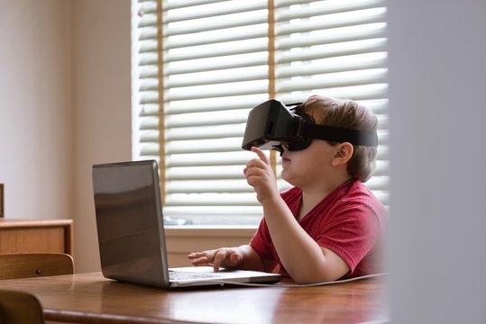 Boy wearing vr glasses while using laptop