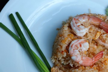 Shrimp fried rice on white plate with spring onion background