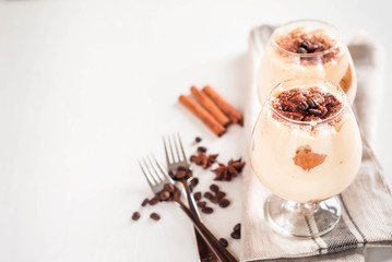 Exquisite Italian dessert tiramisu in cognac glasses on a white