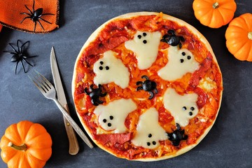 Halloween pizza with ghosts and spiders, above scene with decor on a black background