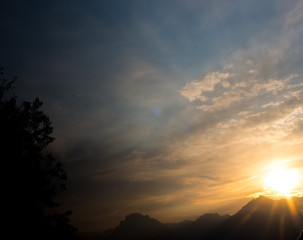 Fototapeta na wymiar Soft filtered sun rays through summer cloudy sky over mountain range