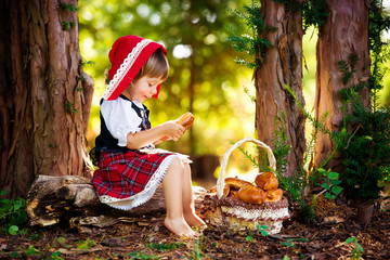 Little Red Riding Hood in the forest sits on a log with a basket of pies.