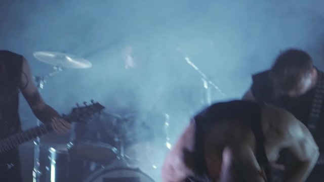 Concert rock band performing on stage with Frontman, guitarists and drummer. Music video punk, heavy metal or rock group.