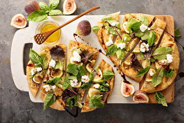 Flatbread pizza with figs, cheese and salad leaves