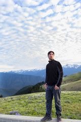 A man standing in front of epic clouds and mountains