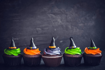 Obraz premium Witch hat cupcakes served on dark background