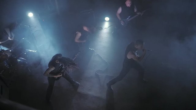 Concert rock band performing on stage with Frontman, guitarists and drummer. Music video punk, heavy metal or rock group.