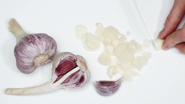 Female hands cutting slicing garlic clove on white board, top view. Food preparing, cooking concept. Timelapse 4K ProRes HQ codec