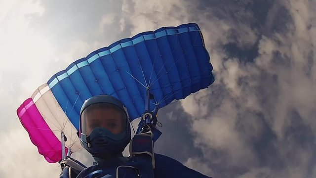 Skydiver in helmet parachuting in sky. Height. Extreme sport. Cloudy sky. Sun. Adrenaline.