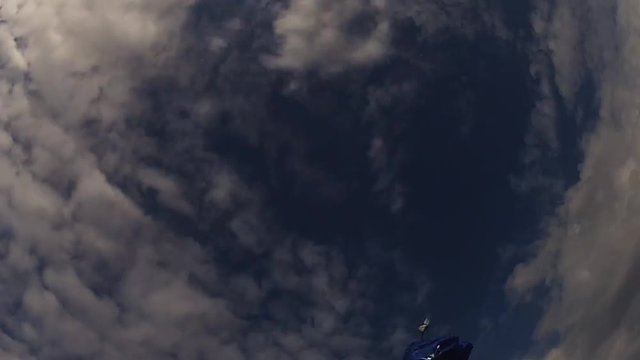 Skydiver in helmet jump from airplane, open parachute in cloudy sky. Height. Extreme sport. Speed.
