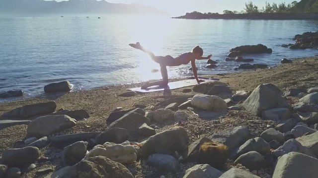 Girl Does Yoga Pose on Knee and Hand against Sun Reflection