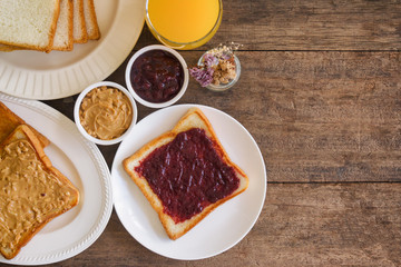 Toast bread with homemade strawberry jam and peanut butter served with orange juice. Homemade toast bread with jam and peanut butter on table for breakfast. Delicious toast bread in top view flat lay.