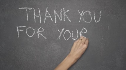 Woman's hand writing "THANK YOU FOR YOUR ATTENTION" with white chalk on blackboard