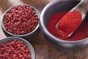 Achiote grains and powder in wooden bowl