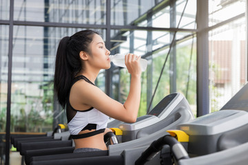 Fototapeta na wymiar Fitness woman drinking water from bottle after run on running machine