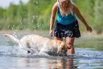 woman plays with a golden retriever in a lake