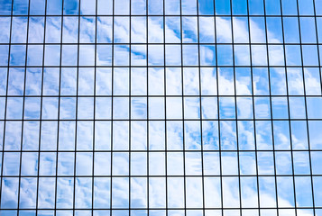 sky and clouds reflected in office glass building facade. modern architecture fragment.
