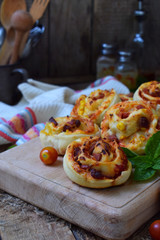 Buns of yeast dough with tomatoes, ham and cheese on a wooden background. Mini pizzas. homemade baking