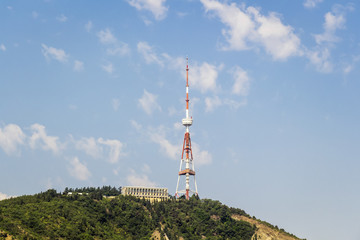 A large television tower stands on top of a high mountain.