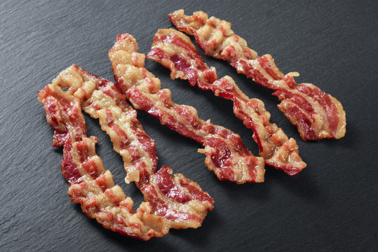 Cooked bacon rashers on the background of a slate board