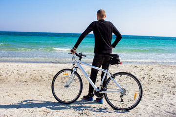 Bicycle rider relaxing on the beach in good weather 