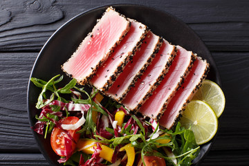 beautiful food: steak tuna in sesame, lime and fresh salad close-up on a plate. Top view horizontal