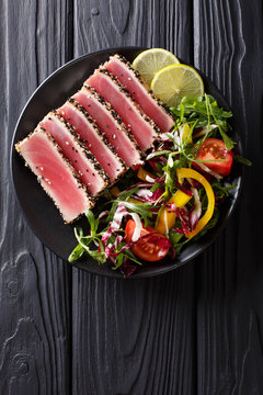 Close up of rare seared Ahi tuna slices with fresh vegetable salad. Top view vertical