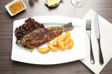 Plate with delicious fried fish on table