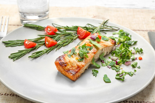 Tasty cooked salmon with herbs on plate, closeup