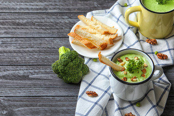 Delicious broccoli soup with walnut in mug on table