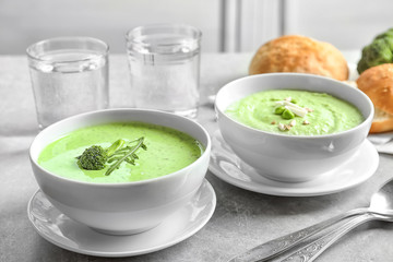 Bowls with delicious broccoli soup on table