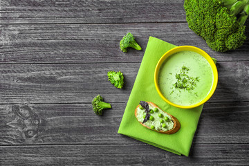 Bowl with delicious broccoli soup on wooden background