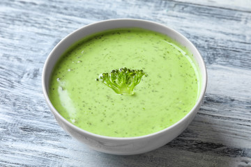Bowl with delicious broccoli soup on wooden background