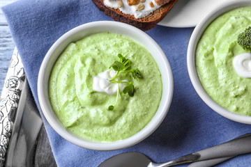 Bowl with delicious creamy broccoli soup on tray