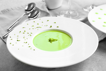 Plate with delicious creamy broccoli soup on table