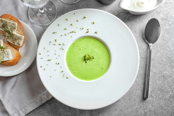 Plate with delicious creamy broccoli soup on table