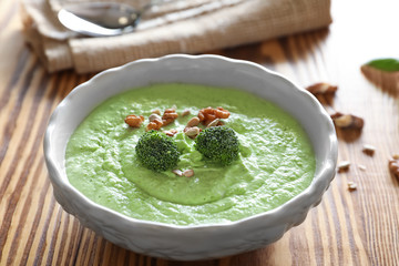 Bowl with delicious creamy broccoli soup on wooden table