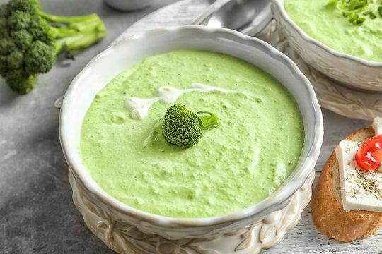 Bowl with delicious broccoli soup on wooden tray