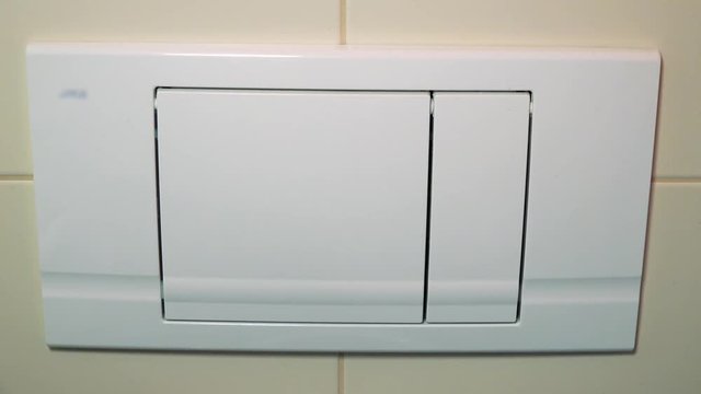 A man presses the flush button in a bathroom - closeup